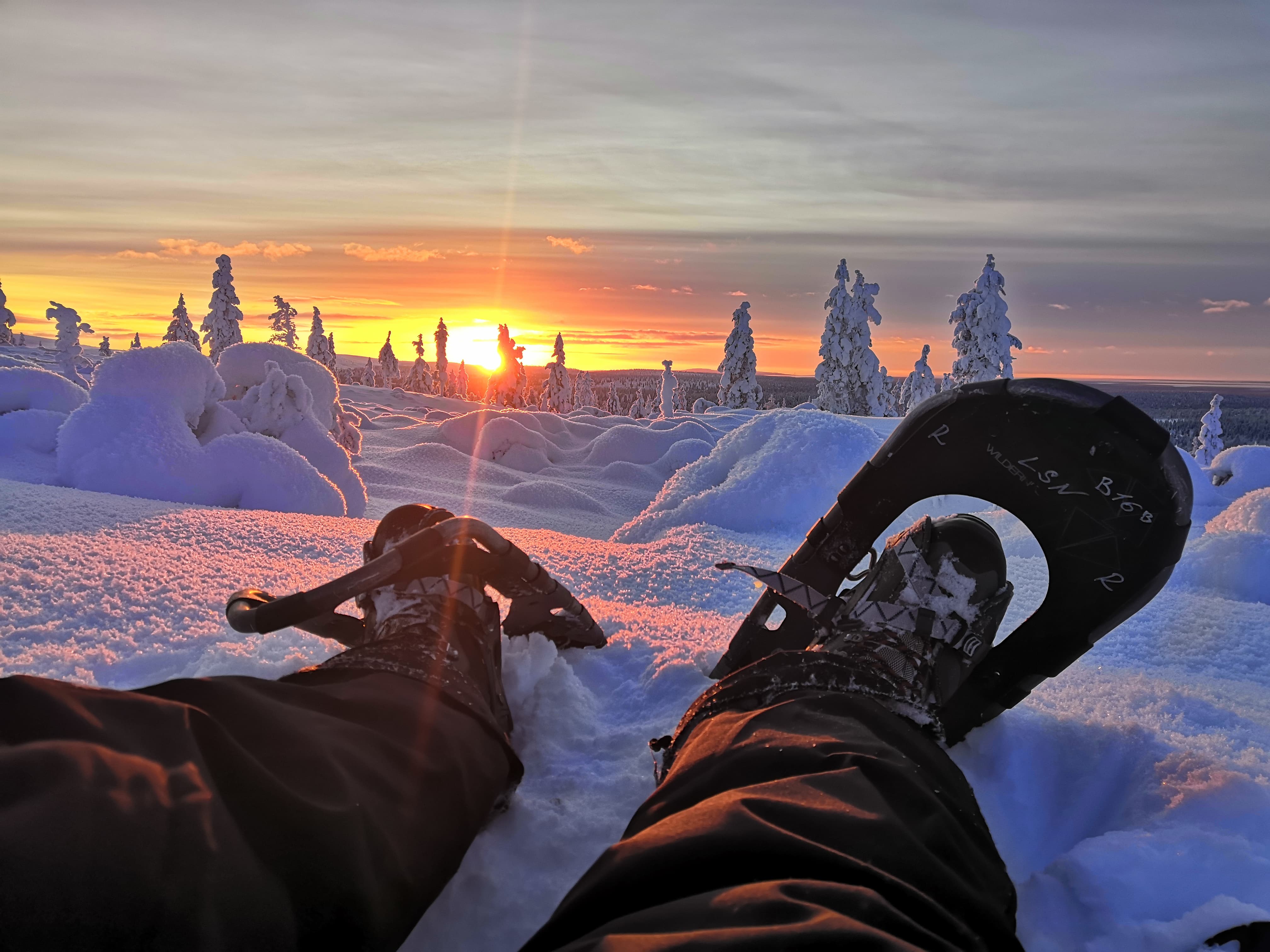 sitting in snowshoes at sunset